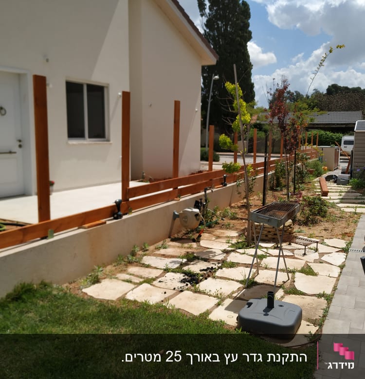 גדר עץ בבנייה ליד גינה עם צינור מים